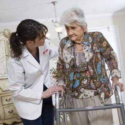 Care taker helps senior with walker during physical therapy at the Oak Park Arms