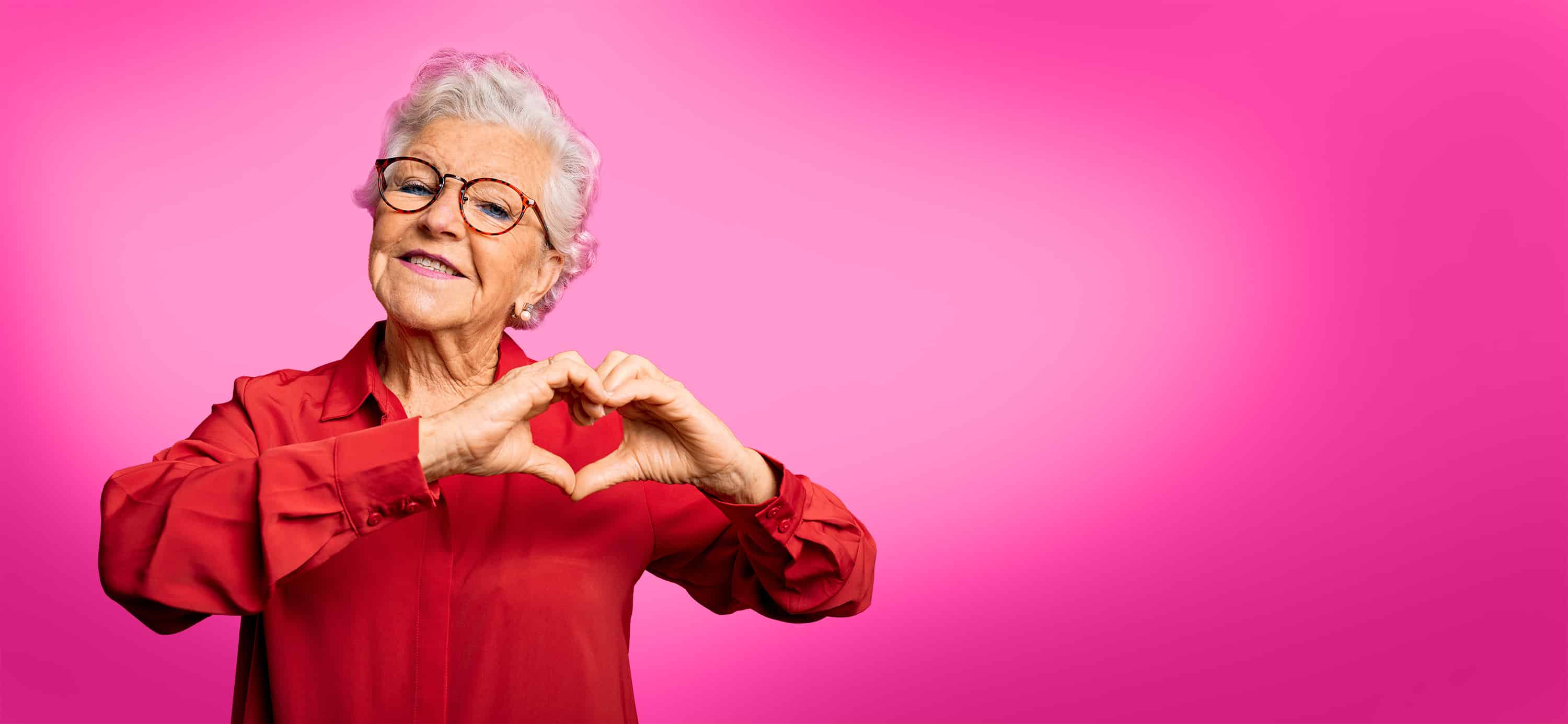 Senior making a heart shape with her hands.