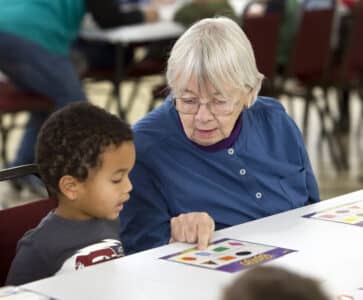Oak Park Arms resident Betsy Davis helps a Kindness Creators preschool student