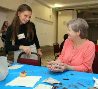 Tatum Matthiesen a student from Brooks Middle School’s BEAT Roots program with Oak Park Arms resident Geneen Sutton plant seeds in a clay ball filled with dirt during a intergenerational gardening event at Oak Park Arms Tuesday, October 14, 2025, in Oak Park, Ill.